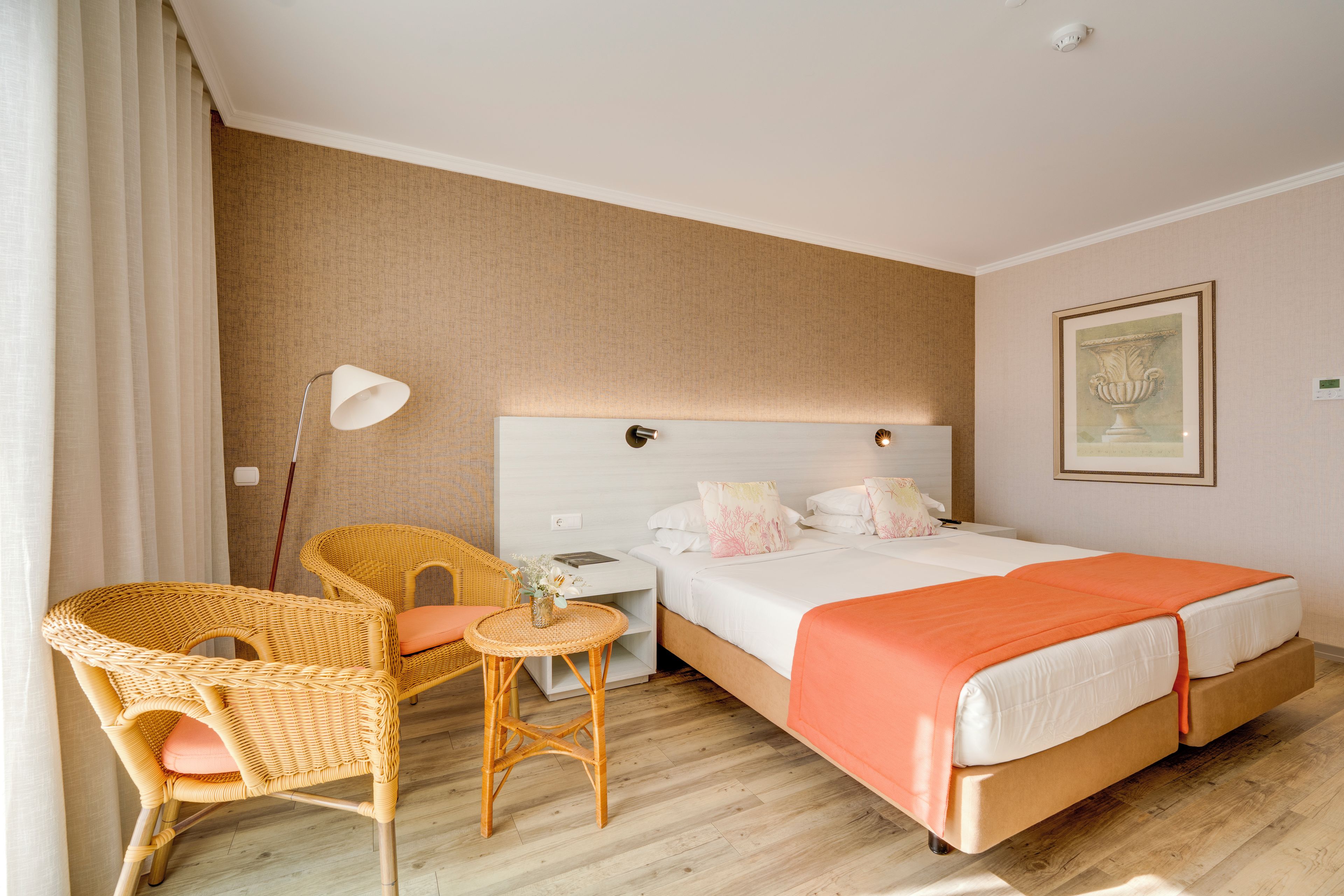 Une chambre d’hôtel avec un lit, deux chaises, une petite table et un tableau au mur.