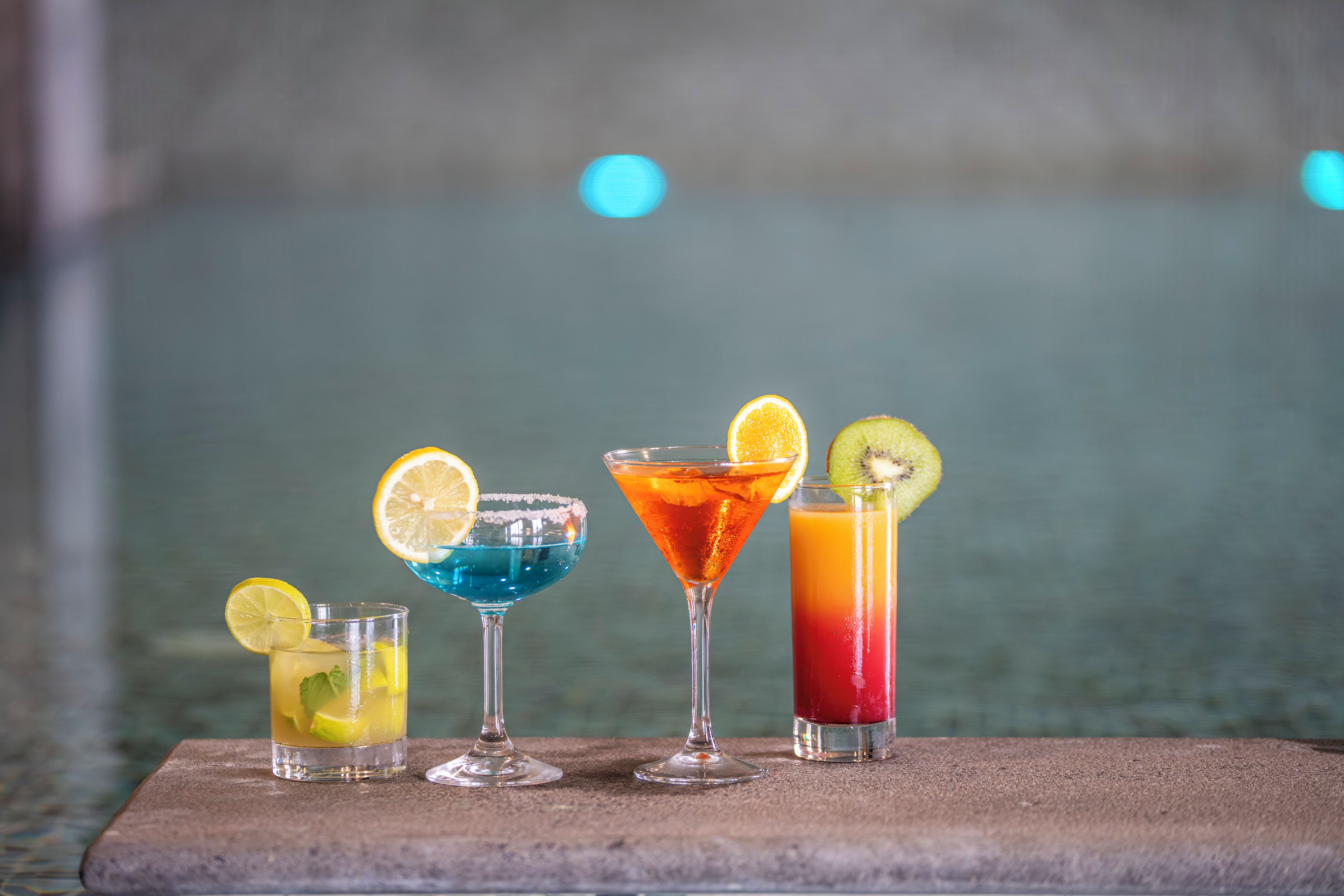 Four different cocktails with garnishes on a table.