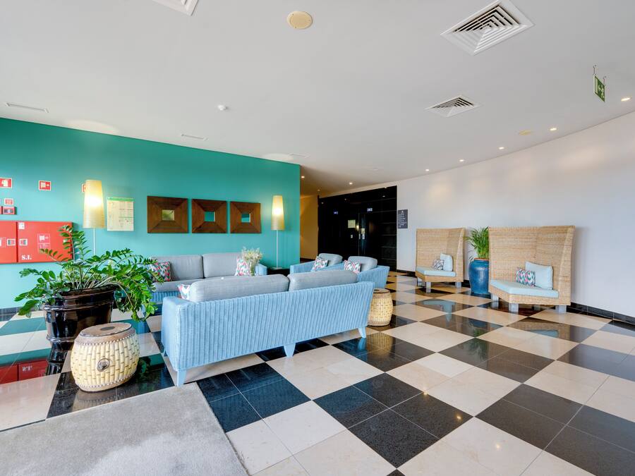 A lobby with a checkered floor, a sofa, a plant, and a wall with emergency exit signs.