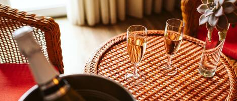 A wicker table with two glasses of champagne and a bottle of champagne.
