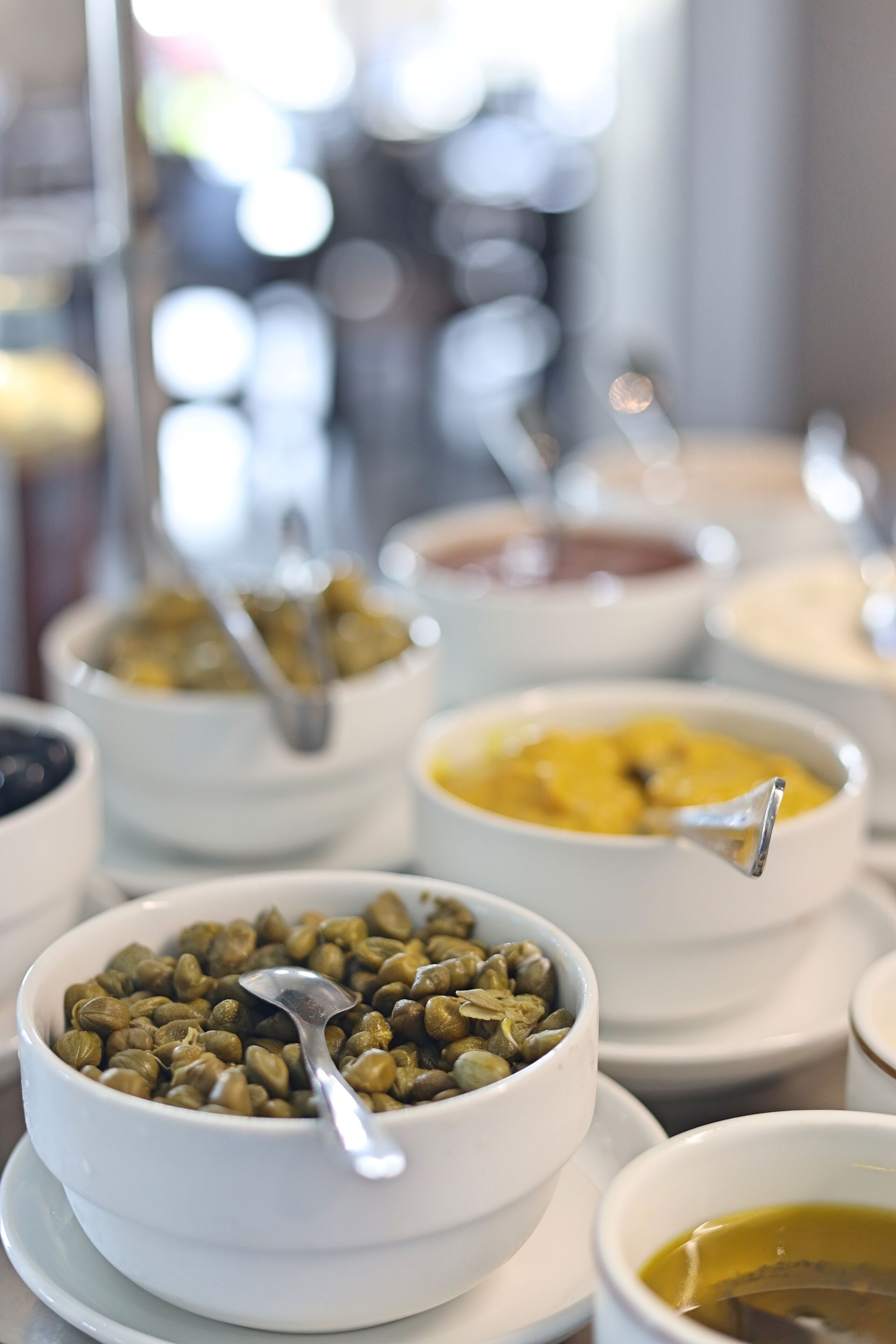 A buffet with various dishes in white bowls, including a bowl of green beans and a bowl of yellow food.