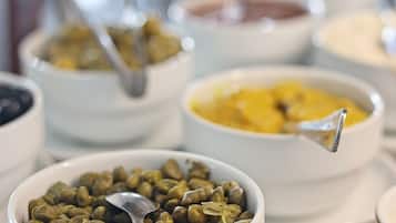 A buffet with various dishes in white bowls, including a bowl of green beans and a bowl of yellow food.