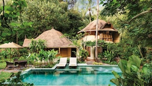 A pool area with lounge chairs and a thatched-roof structure.