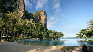 A resort with a pool, palm trees, and a cliff.