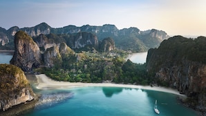 A coastal landscape with a beach, clear turquoise waters, and limestone cliffs. - Rayavadee (Krabi)