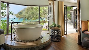 A spa area with a large bathtub, a view of the sea, and a wooden floor. - Rayavadee (Krabi)