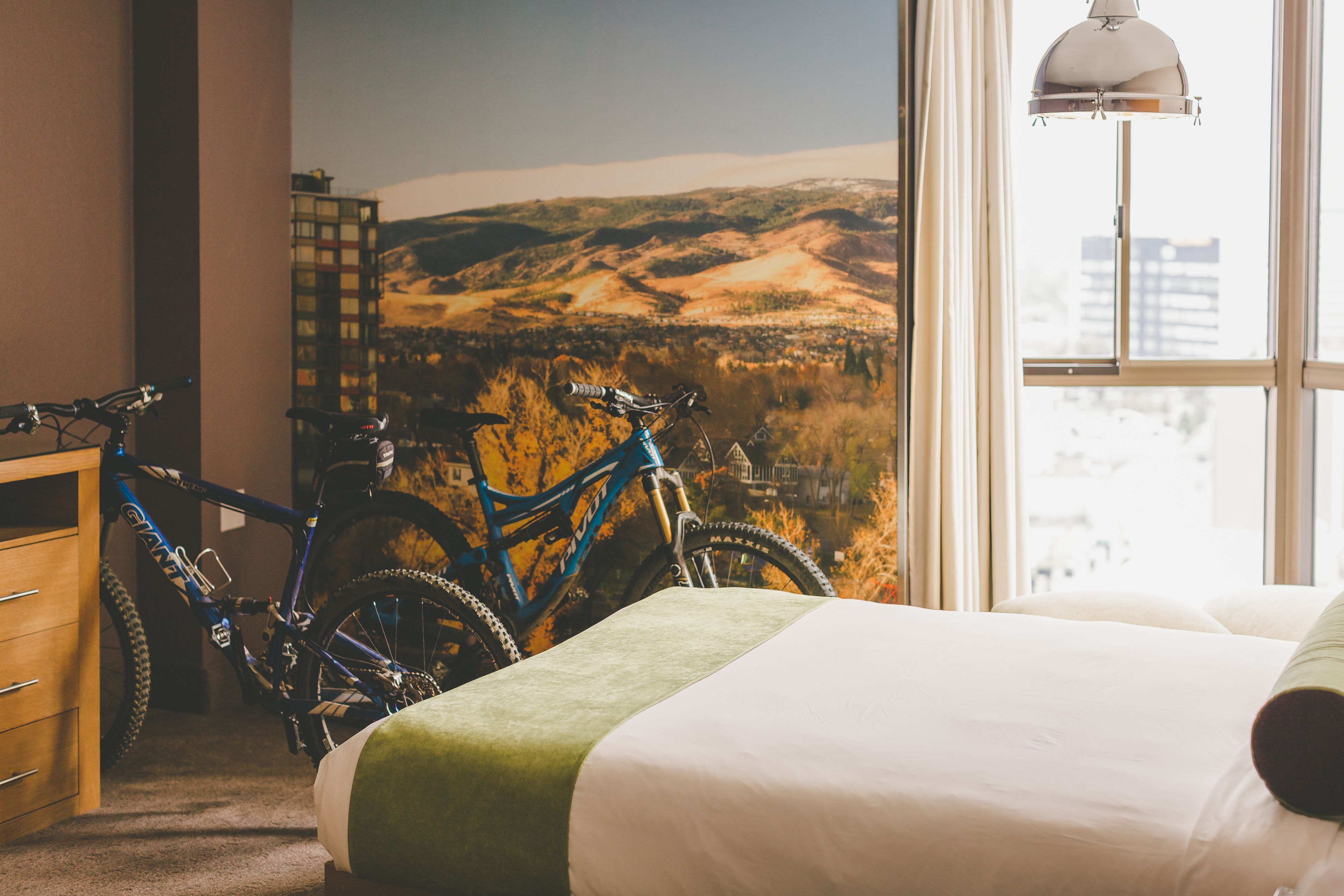 Un dormitorio con una cama, un aparador de madera y una bicicleta apoyada en la pared.