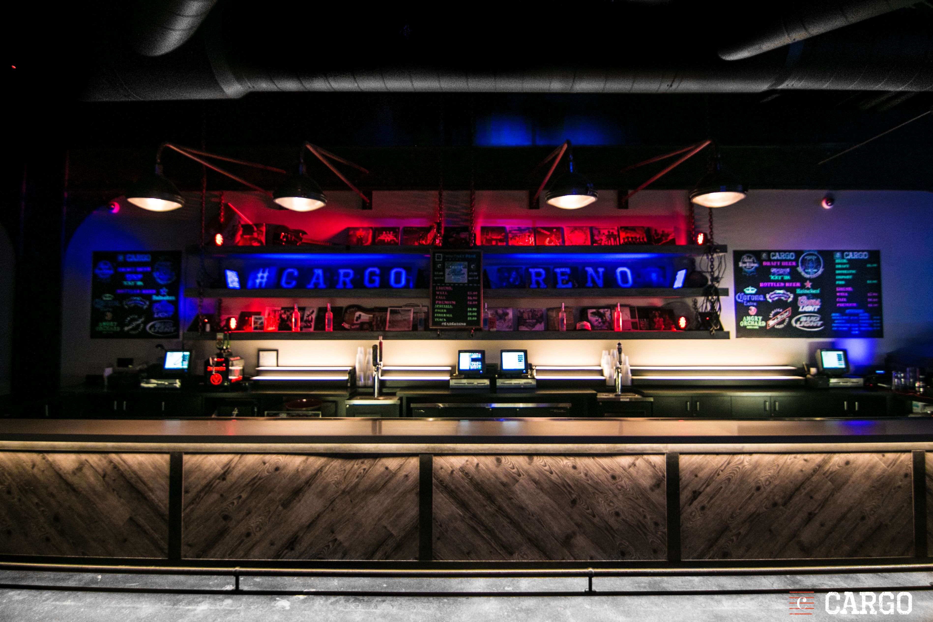 A bar area with a counter and multiple screens displaying information.