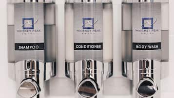 Three bathroom dispensers labeled with Whitney Peak Hotel branding, including shampoo, conditioner, and body wash.