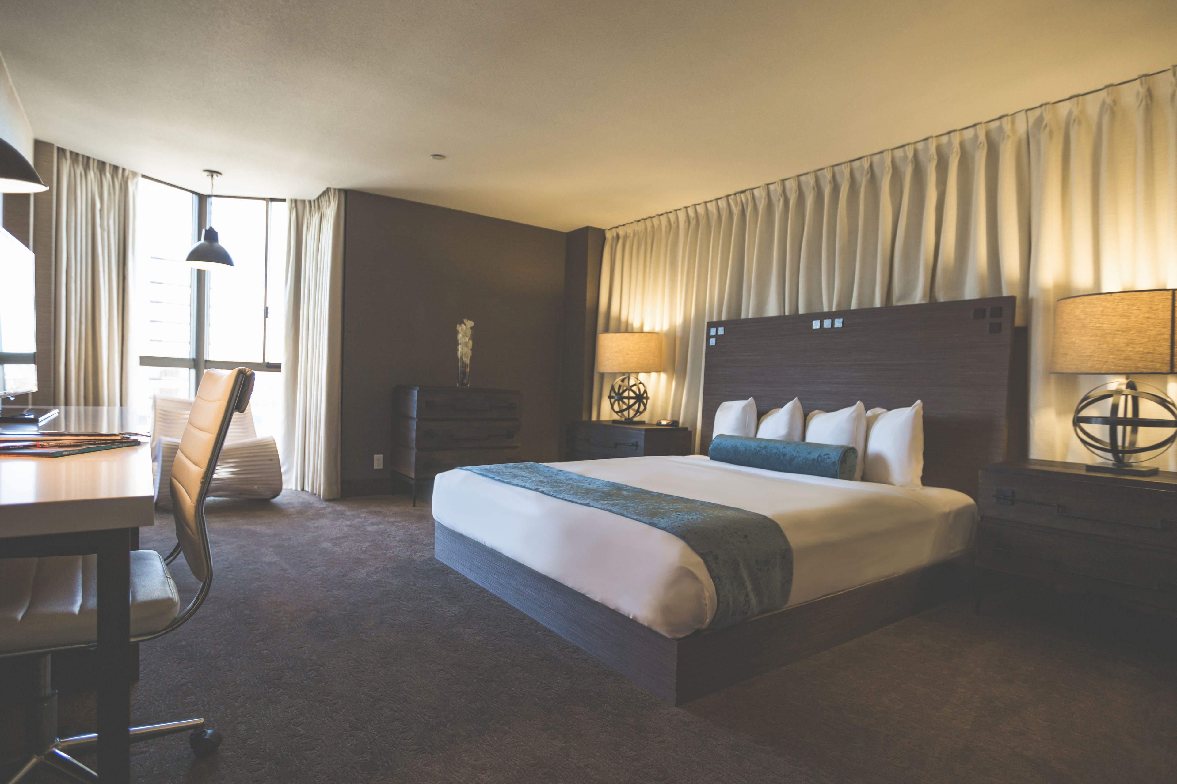A hotel room with a large bed, a desk, and a chair.