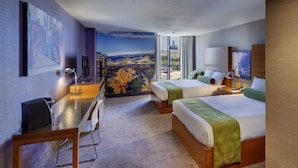 Habitación de hotel con dos camas, un escritorio y un amplio ventanal con vistas panorámicas.