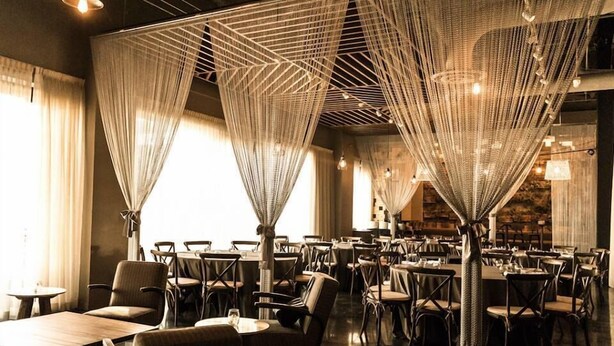 Un restaurante con una decoración moderna, con mesas y sillas dispuestas en un espacio amplio.