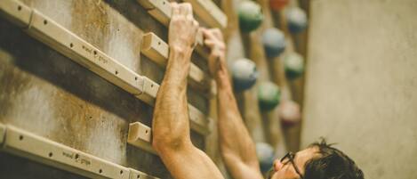 A person climbing a wooden climbing wall with various colored holds.