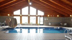 An indoor swimming pool with a wooden ceiling and large windows.