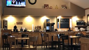A restaurant with a bar area, breakfast hours sign, and a welcome sign.