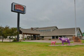 A Fairbridge Inn & Suites building with a large sign, a covered entrance, and two decorative horse statues in the foreground.
