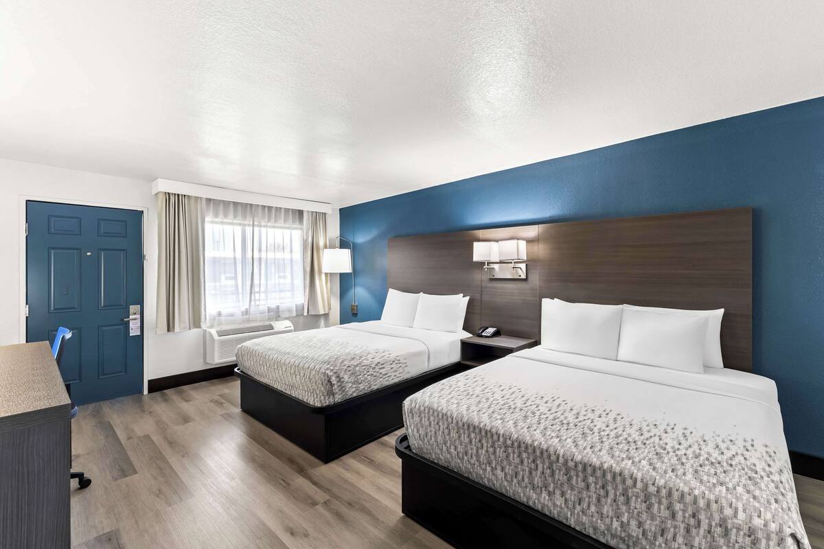 Ein Hotelzimmer mit zwei Betten, einem Schreibtisch und einem Stuhl.