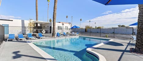 Una piscina con sillas azules y un muro de piedra.