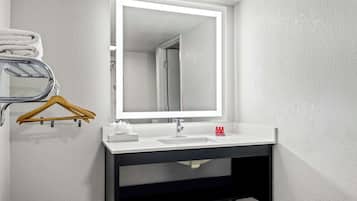 A modern bathroom with a white sink, a mirror, and a towel rack.