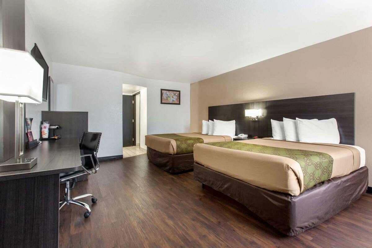 Une chambre d’hôtel avec deux lits, un bureau et une chaise.
