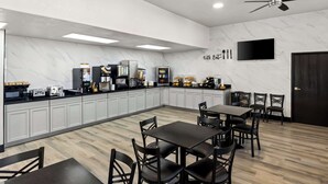 Une cuisine moderne dotée d’un revêtement mural en marbre, d’appareils électroménagers intégrés et d’un téléviseur à écran plat.