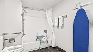 Une salle de bain équipée de toilettes, d’une douche et d’un siège accessible aux personnes en fauteuil roulant.