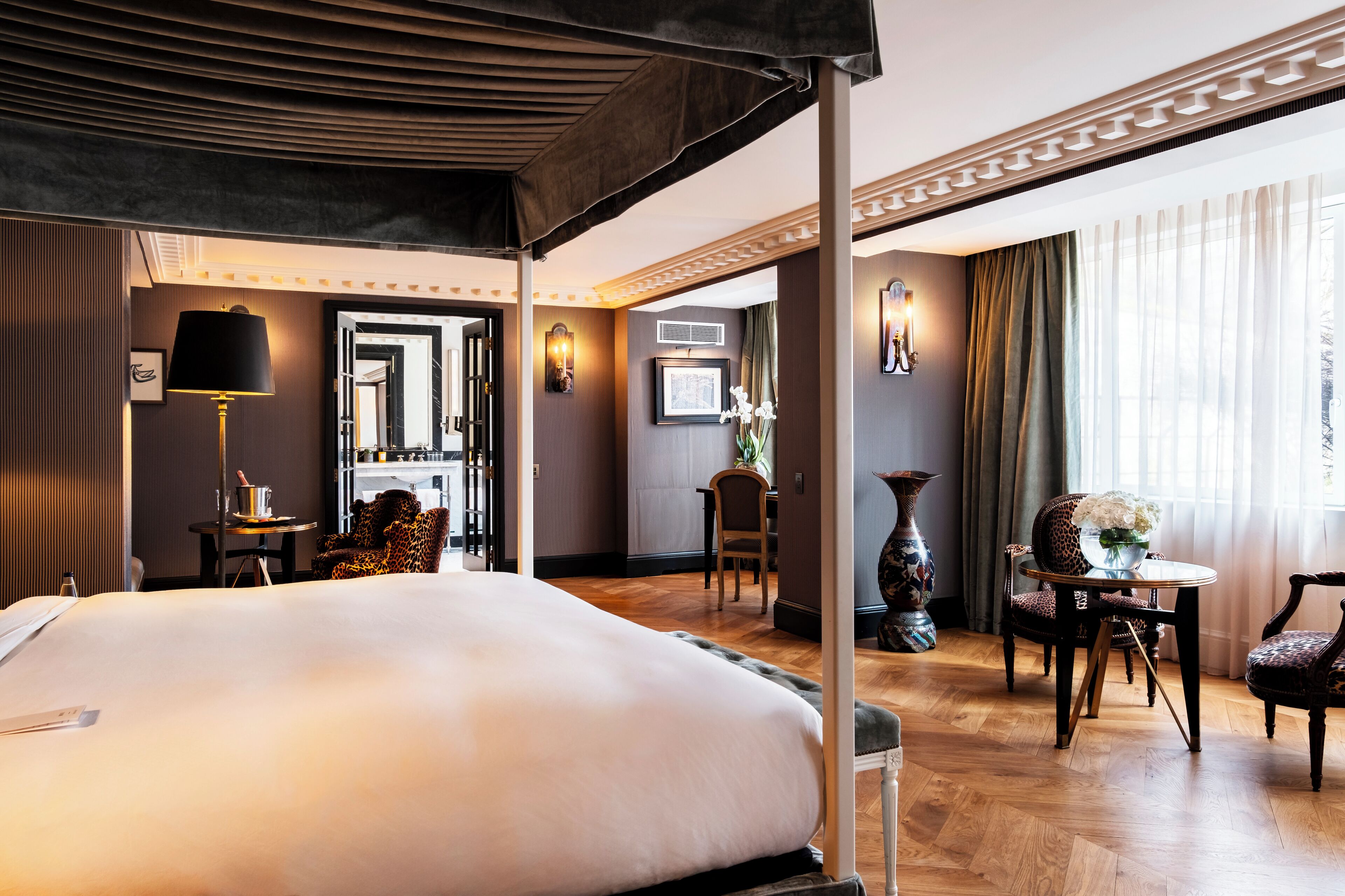 A hotel room with a large bed, a desk, a chair, and a table with a vase of flowers.