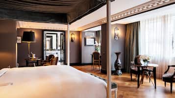 A hotel room with a large bed, a desk, a chair, and a table with a vase of flowers.