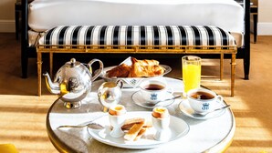A neatly made bed with white linens, a bedside table with a lamp, and a breakfast tray with croissants, coffee cups, and a teapot. -  Hôtel de Berri Champs-Élysées, a Luxury Collection Hotel (Paris)