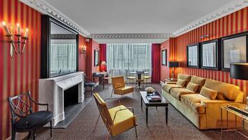 A room with a sofa, chairs, a fireplace, and a dining area.
