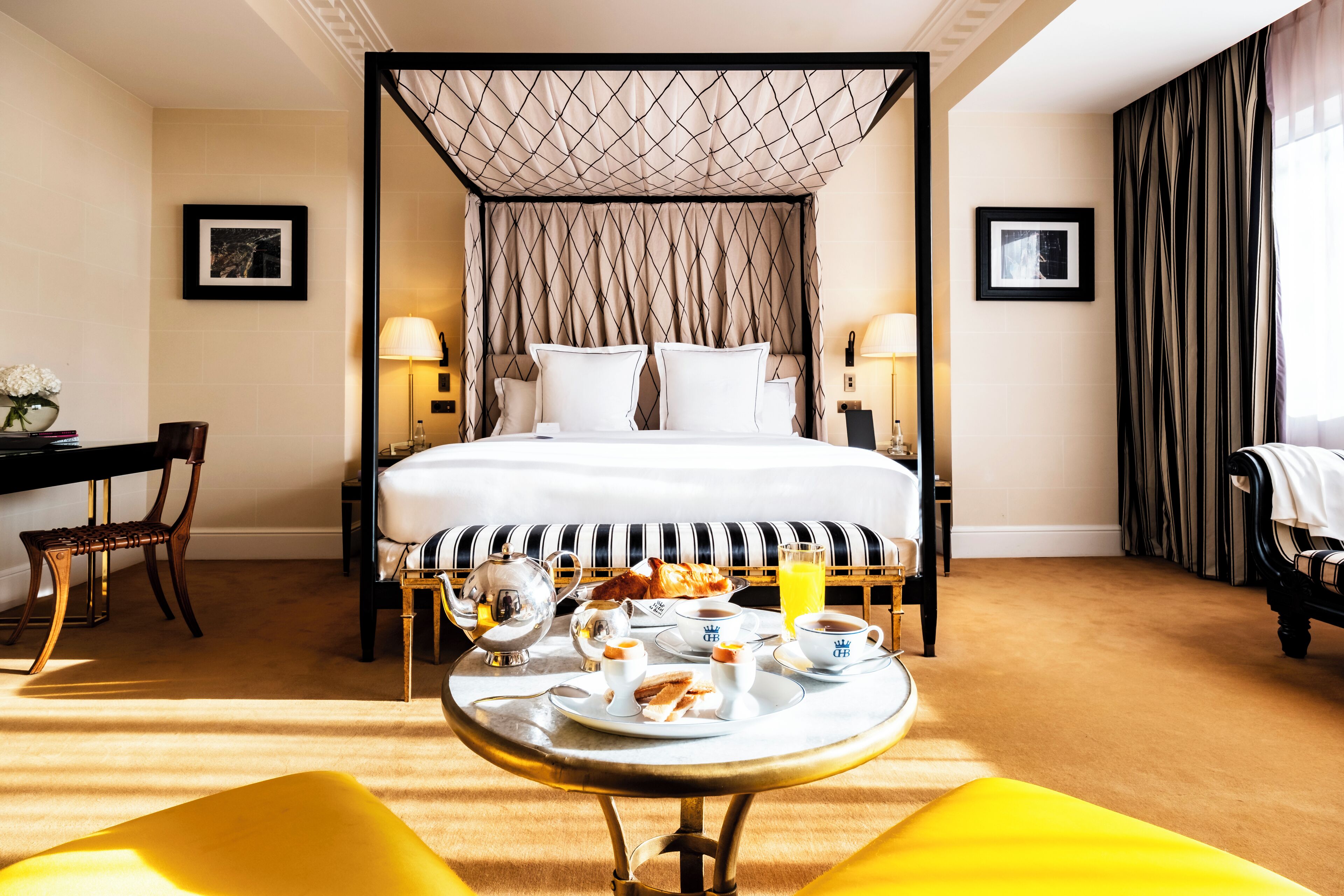 Een hotelkamer met een groot bed, nachtkastjes, een eettafel met ontbijtartikelen, en uitzicht op de kamer.