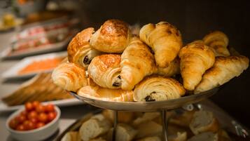 A buffet table with a variety of pastries, including croissants and bread rolls.