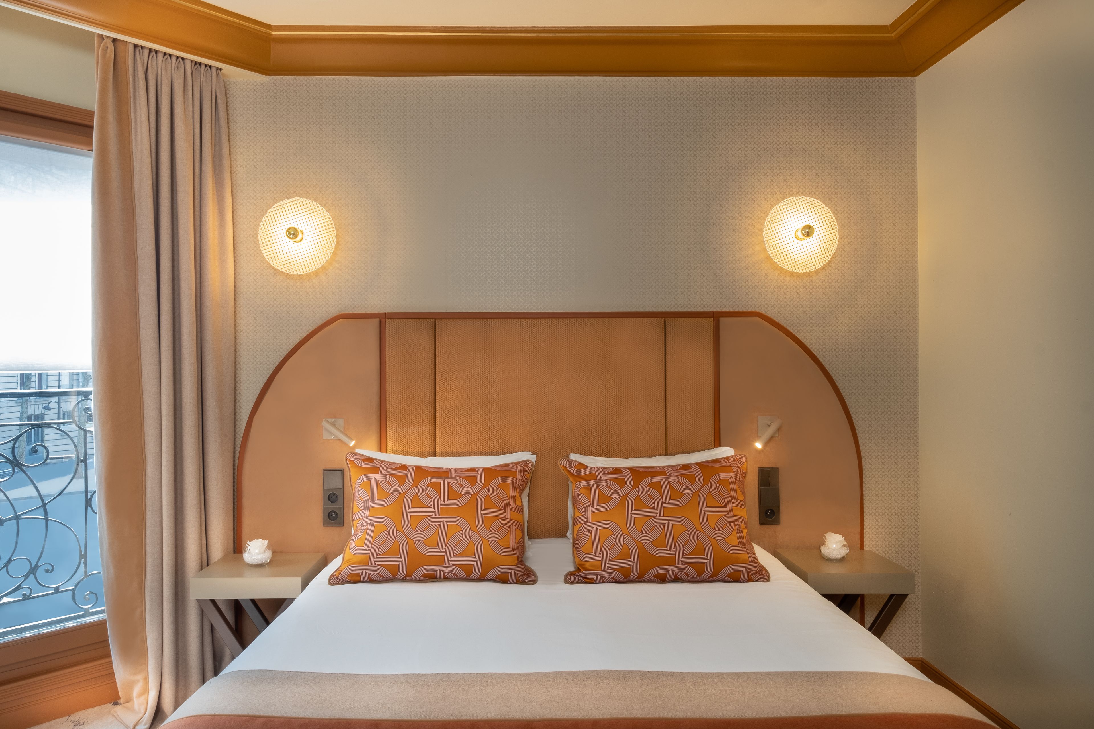 Une chambre d’hôtel avec un grand lit, deux tables de chevet et une tête de lit dotée d’un éclairage intégré.