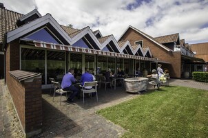 A covered outdoor seating area with brick walls and a glass roof, providing a sheltered space for dining.