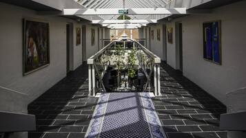 A spacious atrium with a glass ceiling, a patterned carpet, and artwork on the walls.