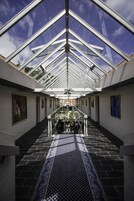 Un amplio atrium con techo de vidrio, alfombra estampada y obras de arte en las paredes.