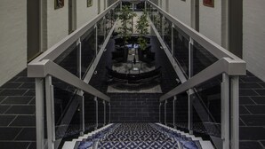 Un interior modern amb sostre de vidre, una escala central i una catifa amb dibuixos.