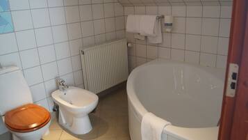 Une salle de bain équipée de toilettes, d’un bidet et d’une baignoire.
