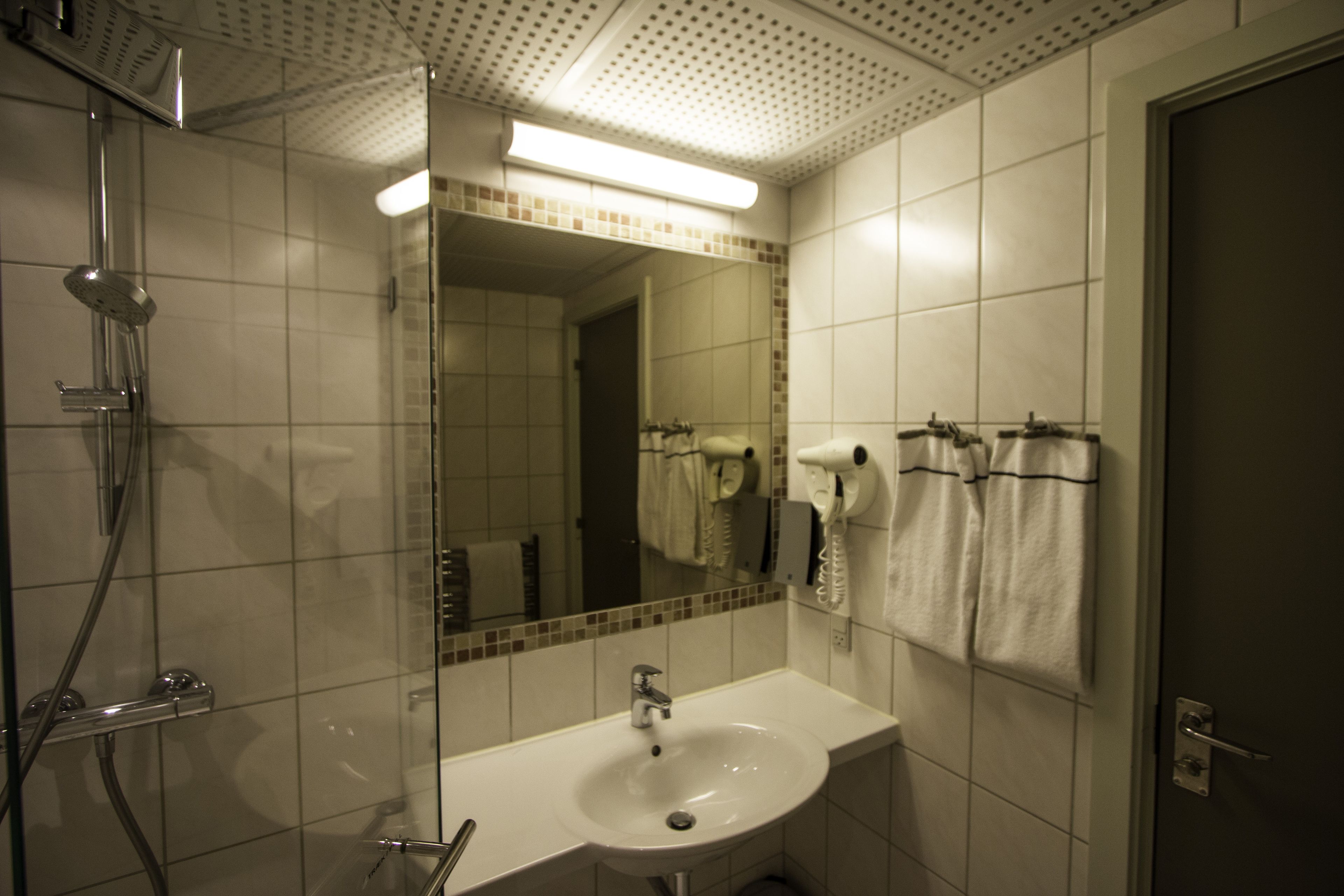 A bathroom with a shower, sink, and towel rack.