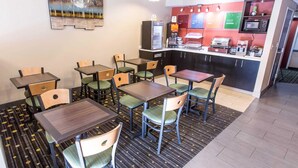A dining area with tables and chairs, a kitchen area with appliances, and a trash bin labeled "TRASH". - Comfort Inn Pittsburgh Crafton (Pittsburgh)