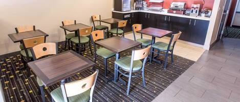 A dining area with tables and chairs, a kitchen area with appliances, and a trash bin labeled "TRASH".