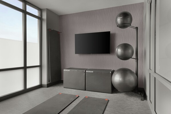 A modern room with a large window, a flat-screen TV, two exercise balls, and a standing lamp.