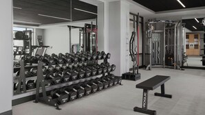 A gym with weightlifting equipment, a bench, and a mirrored wall. - Courtyard by Marriott Louisville Airport (Louisville)