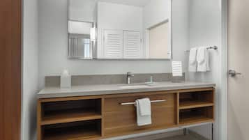 A modern bathroom with a wooden vanity, a large mirror, and a towel rack.