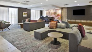 A spacious living area with a large sectional sofa, a round coffee table, and a flat-screen TV mounted on the wall. - Courtyard Somerset by Marriott (Somerset)