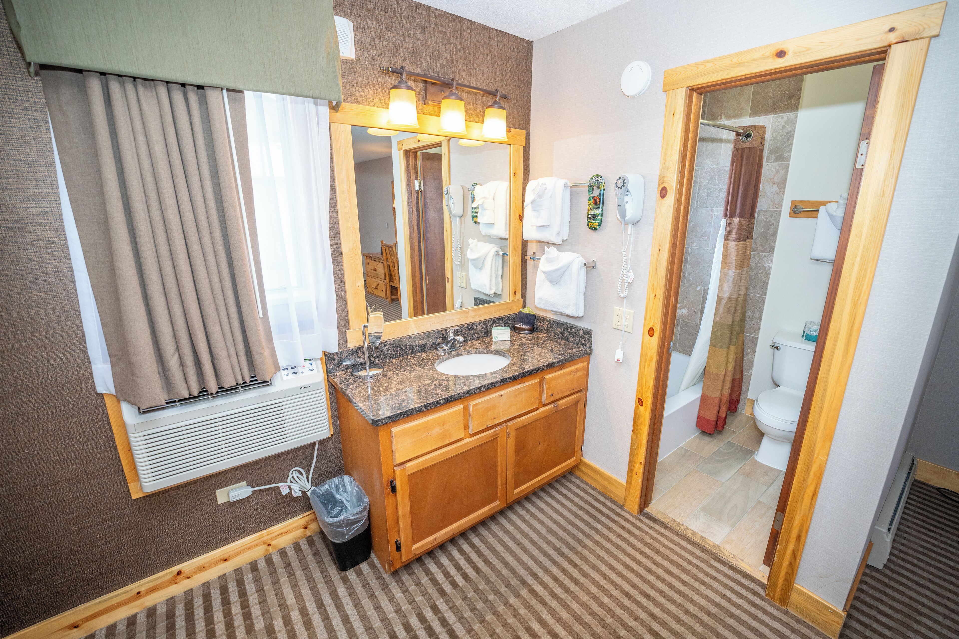 Een hotelbadkamer met een houten wastafel, een wastafel, een spiegel en een douchehoek.