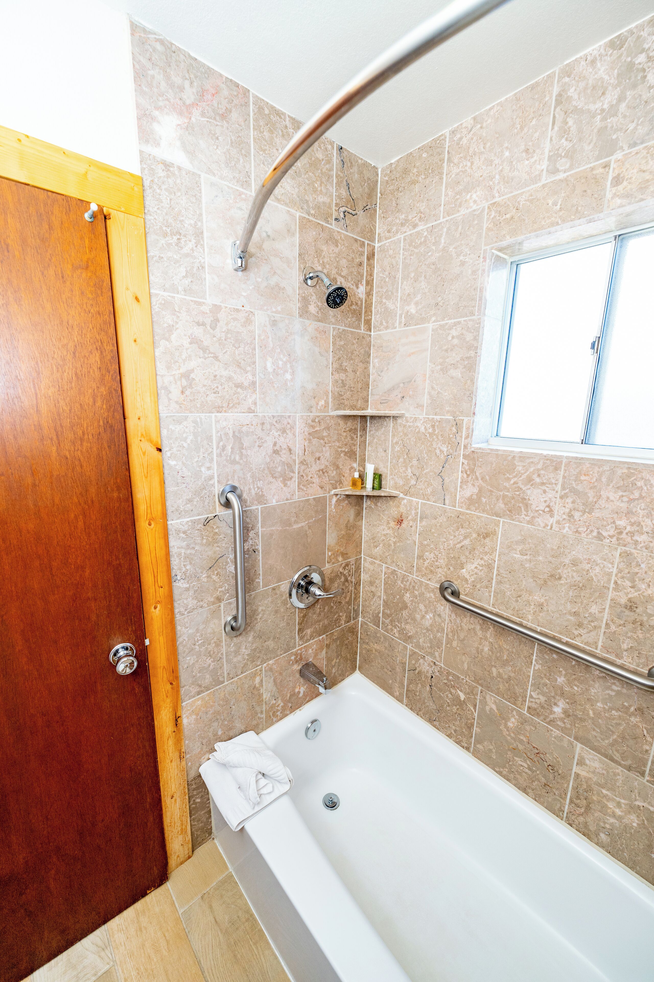 A bathroom with a bathtub, shower, and a window.