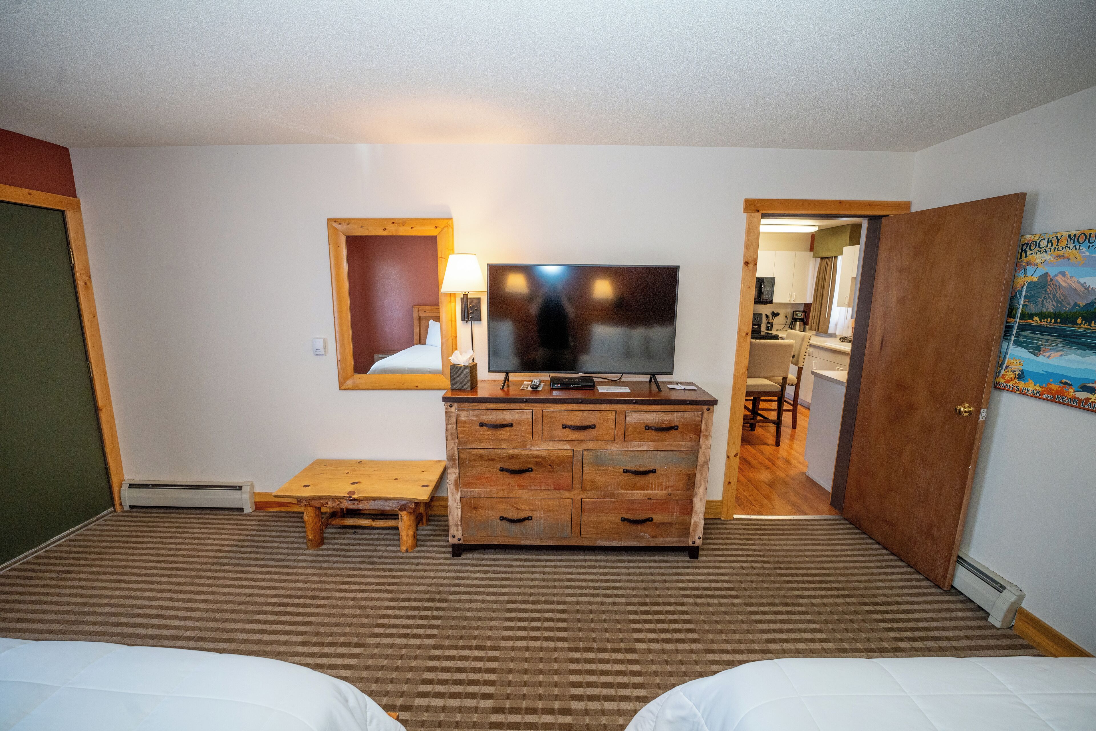 Una habitación de hotel con una cama, un aparador de madera, un televisor y una pequeña mesa.