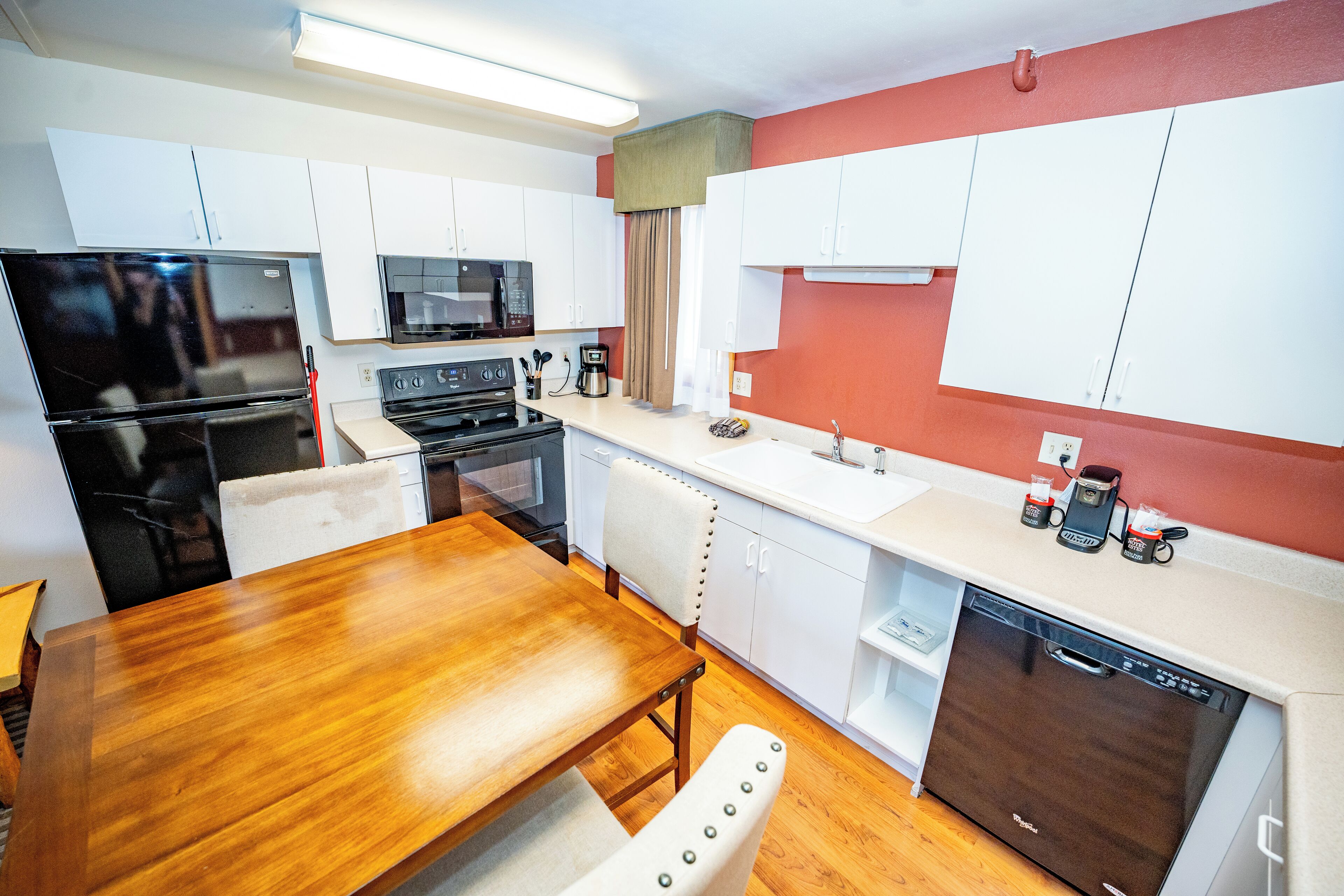 Una cocina moderna con armarios blancos, una mesa de comedor de madera y un lavavajillas integrado.