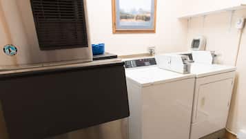 A laundry area with a stainless steel washer and dryer, a window with a mountain view, and a blue basin on the counter.